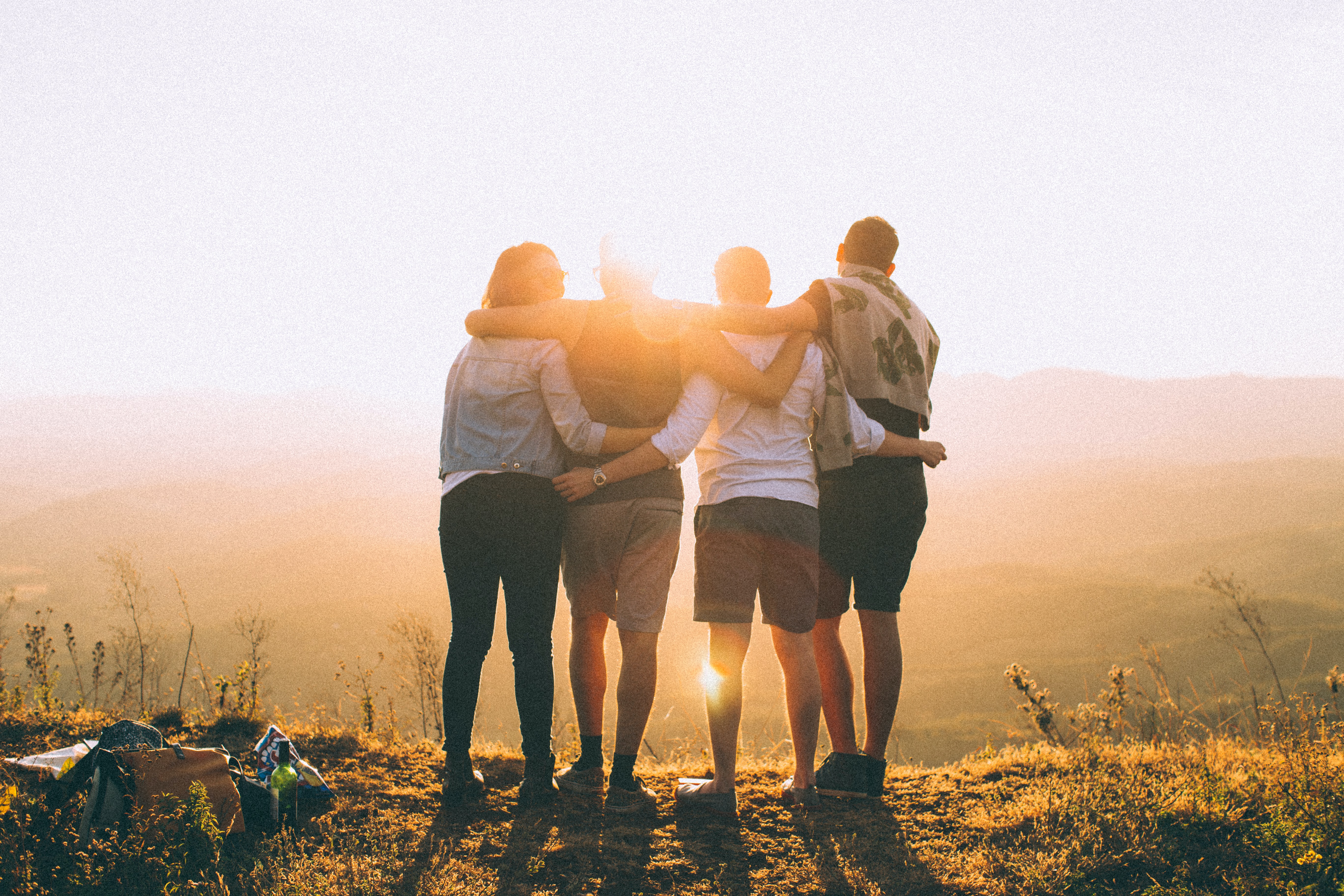 Imagens com 4 jovens de costa assistindo o pôr do sol