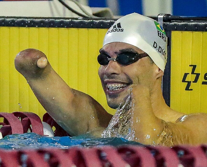 Daniel Dias comemorando o tempo dos 100m livre dentro da água, com óculos e touca de natação.