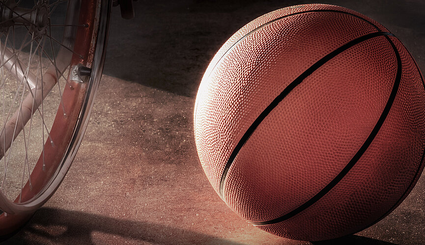 Cadeira de rodas ao lado de bola de basquete.