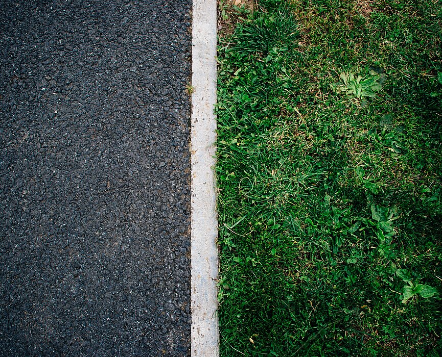 Do lado esquerdo, o asfalto. Do lado direito, a grama. Uma linha branca separa os dois. 