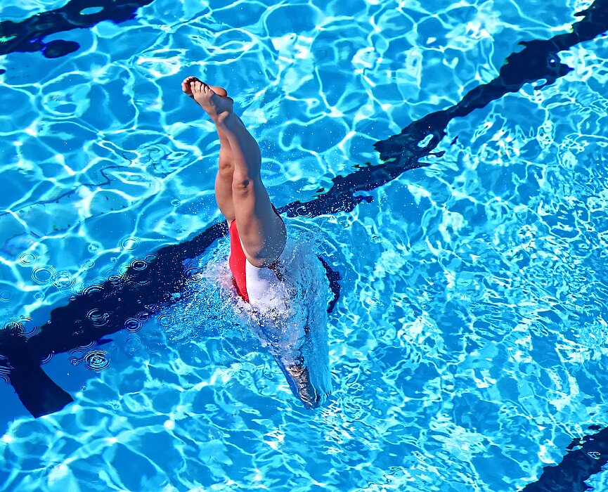 Atleta treinando nado artístico na piscina 