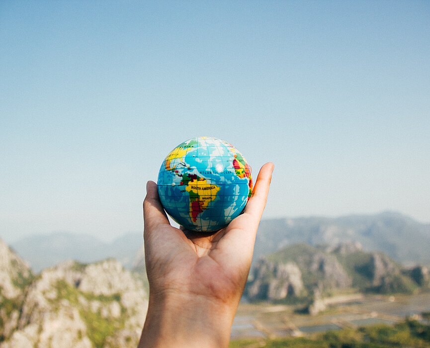 Imagem com uma pessoa segurando um globo terrestre.
